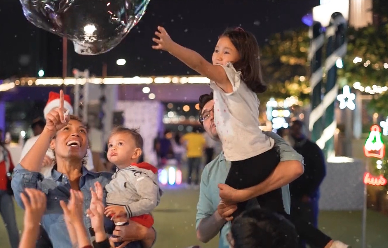 Families catching bubbles at a festive evening event
