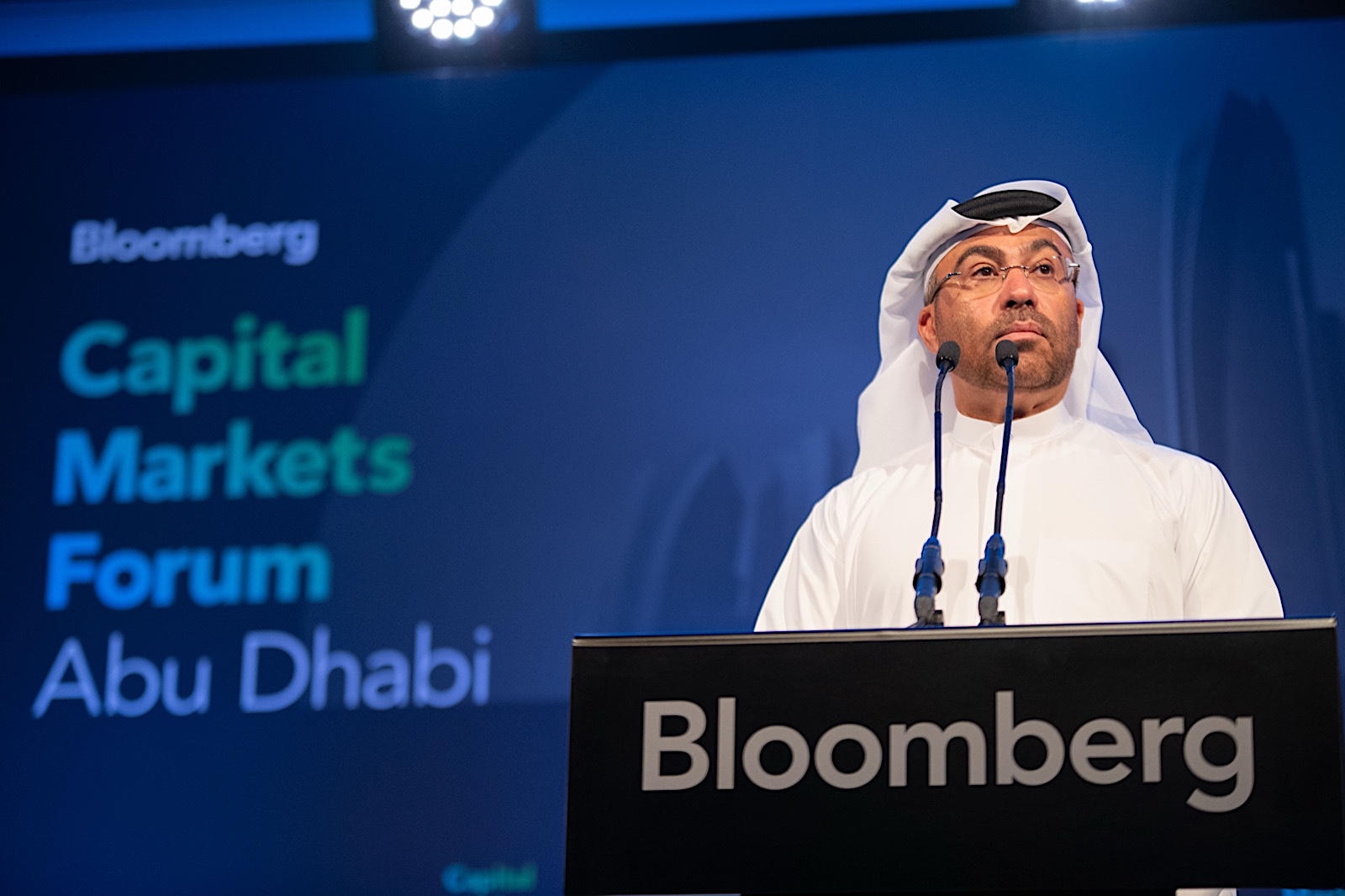 Speaker at a lectern on stage at a finance forum in Abu Dhabi