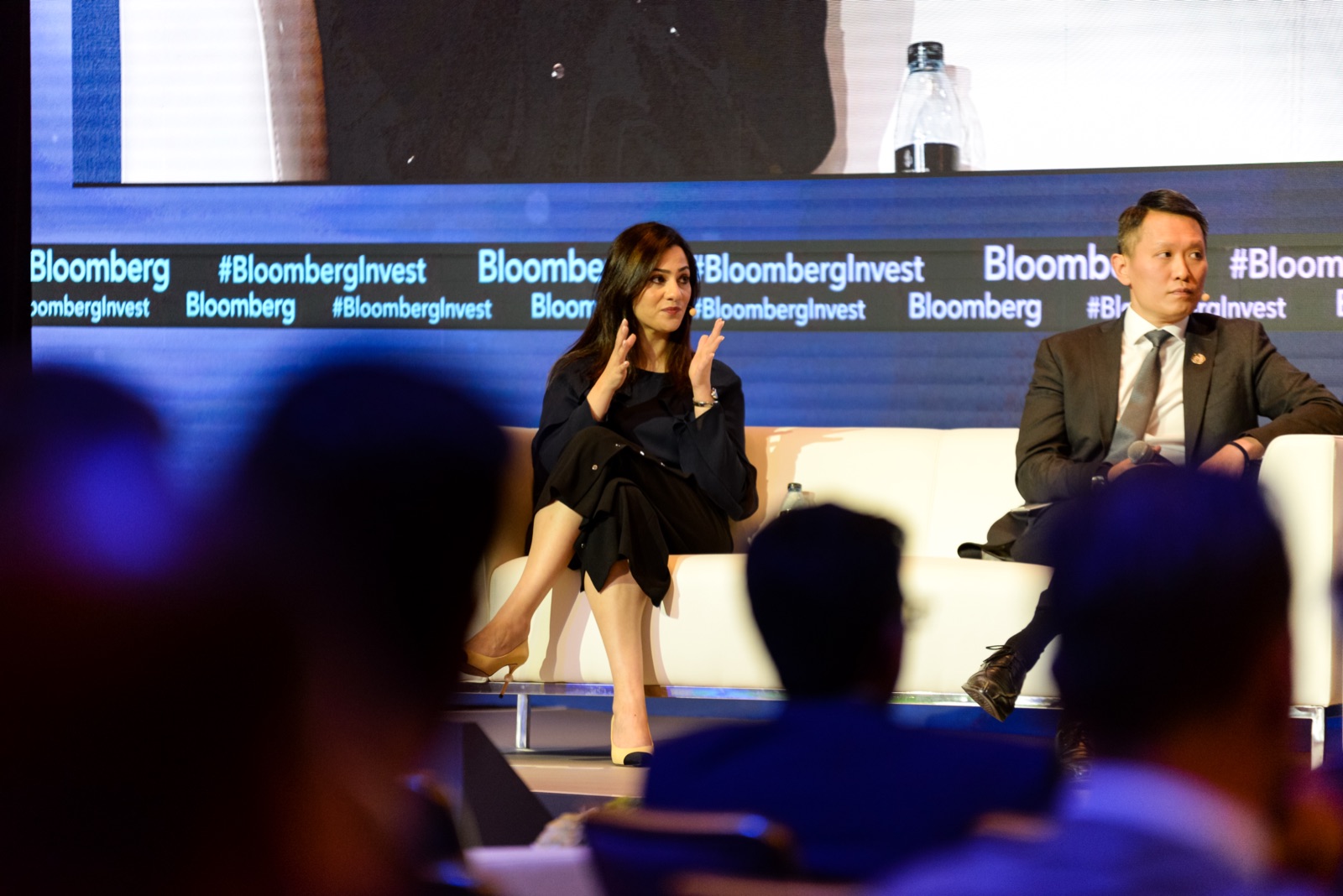 Panel speakers on stage at a finance conference, audience in the foreground