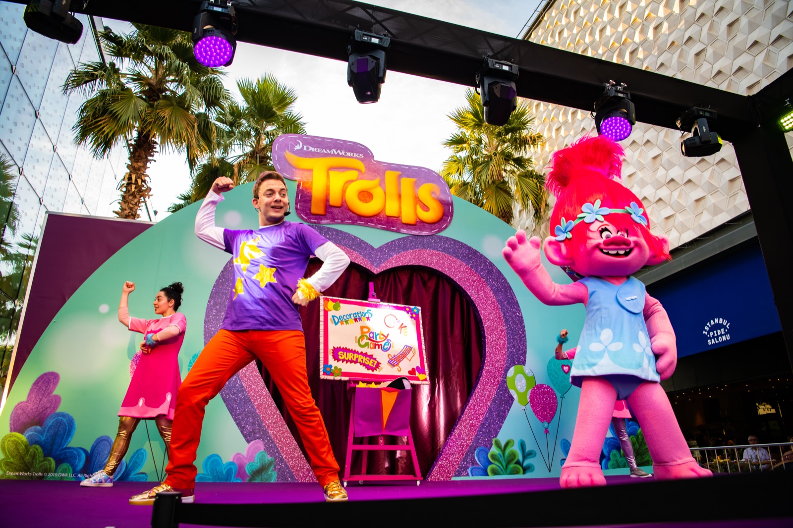 Performers and a costumed character dancing on an outdoor family-show stage