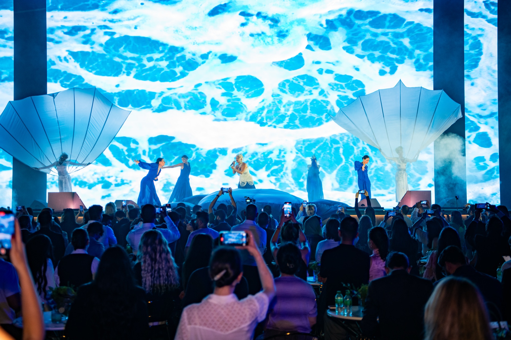 Live stage show in front of an ocean LED wall, audience filming on their phones